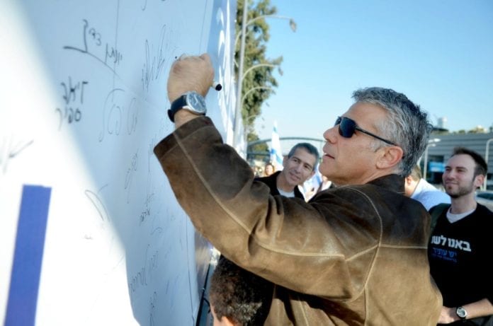 Yair Lapid signerer en av Yesh Atids valgkampplakater for full allmenn verneplikt. (Foto: Yair Lapids Facebook-side) Yair Lapid signerer en av Yesh Atids valgkampplakater for full allmenn verneplikt. (Foto: Yair Lapids Facebook-side)