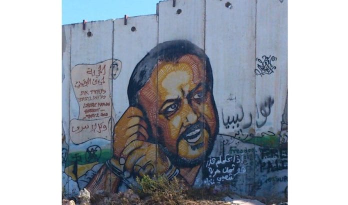 Den portretterte mannen på sikkerhetsbarrieren mellom Jerusalem og Ramallah er den fem ganger drapsdømte terrorlederen Marwan Barghouti. Han er en populær presidentkandidat. (Foto: Wikimedia Commons.) Den portretterte mannen på sikkerhetsbarrieren mellom Jerusalem og Ramallah er den fem ganger drapsdømte terrorlederen Marwan Barghouti. Han er en populær presidentkandidat. (Foto: Wikimedia Commons.)