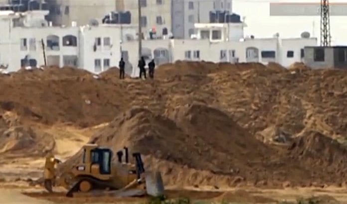 Væpnede og maskerte menn fra Hamas graver ved grensegjerdet mot Israel. (Foto: Skjermdump fra Ynetnews.com web-tv) Væpnede og maskerte menn fra Hamas graver ved grensegjerdet mot Israel. (Foto: Skjermdump fra Ynetnews.com web-tv)