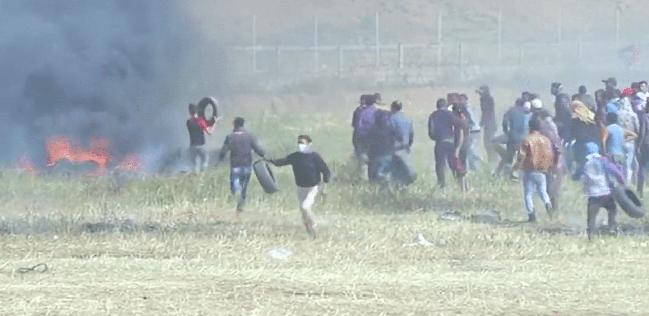 Palestinere setter fyr på dekk like ved grensen. I bakgrunnen sees de israelske grensevaktene. (Foto: Skjermdump)