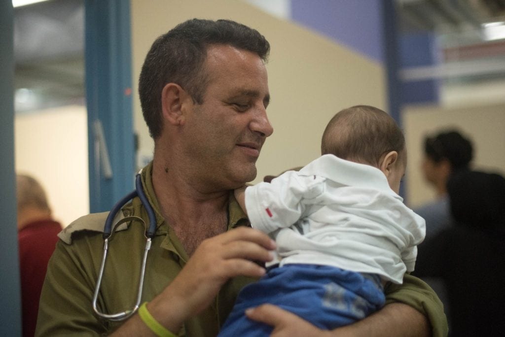 En israelsk helsearbeider med et syrisk barn. (Foto: IDF)