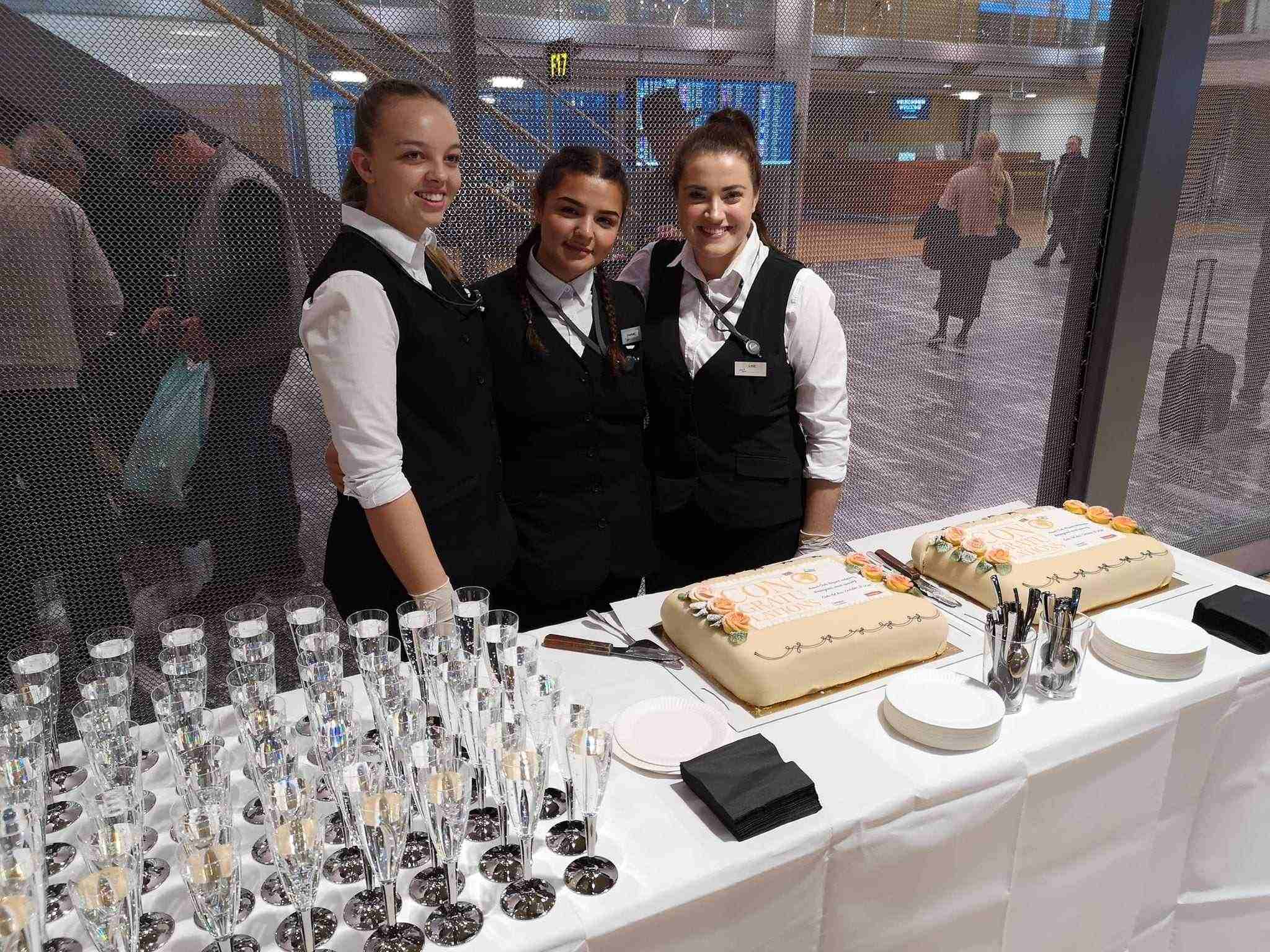 Kake og drikke blir servert av disse unge damene fra Norwegian.