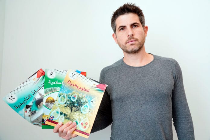 Arik Agassi, forskningsleder ved IMPACT-se, viser fram noen av de palestinske skolebøkene som fremmer jihad og motarbeider fred. (Foto: IMPACT-se)